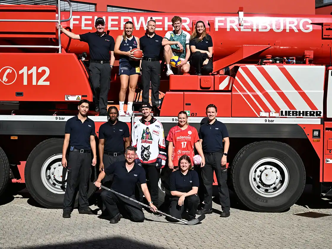 Feuerwehrleute und Spitzensportler mit Löschfahrzeug